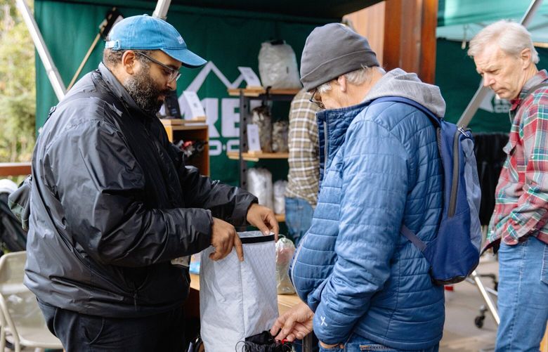 Allmansright co-founder Livio Melo shows off his business’s ultralight backpacking gear to a prospective customer at REI’s Founders Market in October 2022. The event at the company’s flagship store in Seattle highlighted participants in the co-op’s Path Ahead Ventures program, a business accelerator for outdoor industry entrepreneurs of color.