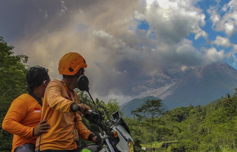 Men watch as Mount Merapi releases volcanic materials during an eruption in Sleman, Indonesia, Saturday, March 11, 2023. (AP Photo/Slamet Riyadi) XTS102 XTS102