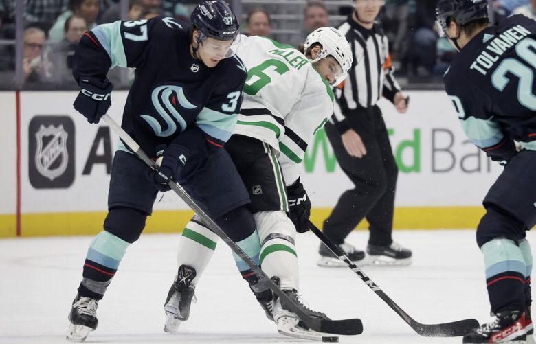 Seattle Kraken center Yanni Gourde (37) and Dallas Stars defenseman Colin Miller (6) battle for control of the puck during the first period of an NHL hockey game, Saturday, March 11, 2023, in Seattle. (AP Photo/John Froschauer) WAJF103 WAJF103