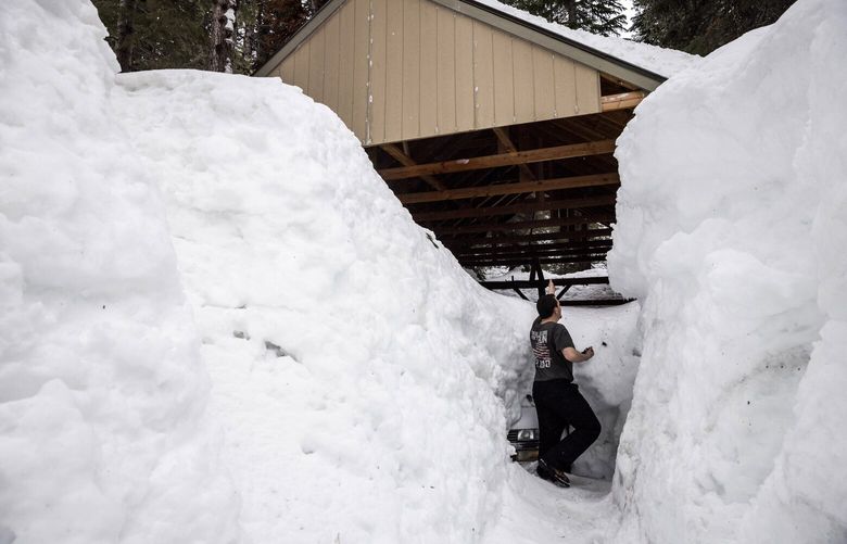 Resident Alex Bernard is seen outside a carport surrounded by snow in Kingvale, Calif., Friday, March 10, 2023. (Stephen Lam/San Francisco Chronicle via AP) CAFRA591 CAFRA591