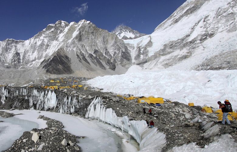 FILE – Tents are set up for climbers on the Khumbu Glacier, with Mount Khumbutse, center, and Khumbu Icefall, right, seen in background, at Everest Base Camp in Nepal on April 11, 2015. As glaciers melt and pour massive amounts of water into nearby lakes, 15 million people across the globe live under the threat of a sudden and deadly outburst flood, a new study finds. (AP Photo/Tashi Sherpa, File)