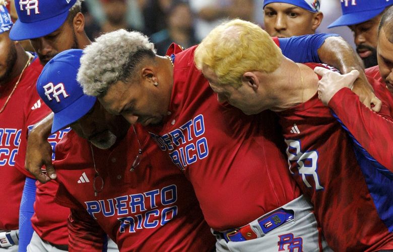 Puerto Rico pitcher Edwin Diaz (39) is helped by team pitching coach Ricky Bones and medical staff after a World Baseball Classic game against the Dominican Republic, Wednesday, March 15, 2023, in Miami. (David Santiago/Miami Herald via AP) FLMIH203 FLMIH203