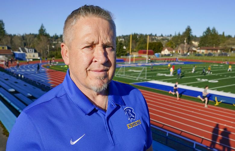 Joe Kennedy, a former assistant football coach at Bremerton High School in Bremerton, Wash., poses for a photo March 9, 2022, at the school’s football field. After losing his coaching job for refusing to stop kneeling in prayer with players and spectators on the field immediately after football games, Kennedy will take his arguments before the U.S. Supreme Court on Monday, April 25, 2022, saying the Bremerton School District violated his First Amendment rights by refusing to let him continue praying at midfield after games. (AP Photo/Ted S. Warren) WATW301