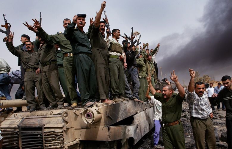 FILE — Iraqi soldiers celebrate on an American tank that was destroyed in fighting on the highway in Doura, a southern suburb of Baghdad, March 20, 2003. From the first night of bombing through the official American withdrawal, photographers with The New York Times and other news organizations chronicled the ordeal of the war in Iraq. (Tyler Hicks/The New York Times) XNYT30 XNYT30