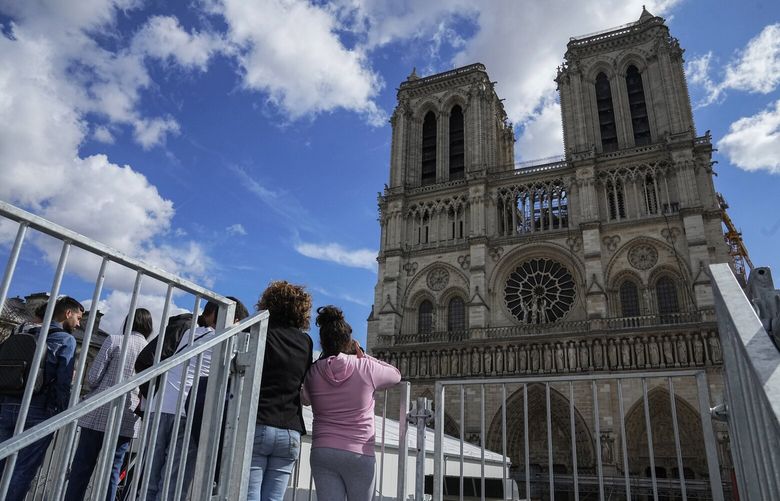 FILE – People have a close look of Notre Dame cathedral as they visit the rebuilding site during Heritage Day in Paris, Saturday, Sept. 17, 2022. France’s Notre Dame Cathedral’s reconstruction is progressing enough to allow its reopening to visitors and masses at the end of next year, less than six years after the after the shocking fire that tore through its roof, French officials said as an exhibit pays tribute to hundreds of artisans working on it. (AP Photo/Michel Euler, File) PAR105 PAR105