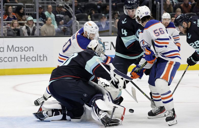 Edmonton Oilers right wing Kailer Yamamoto (56) and center Derek Ryan (10) battle for the puck with Seattle Kraken defenseman Justin Schultz (4) and goaltender Philipp Grubauer (31) during the second period of an NHL hockey game, Saturday, March 18, 2023, in Seattle. (AP Photo/John Froschauer) WAJF109 WAJF109
