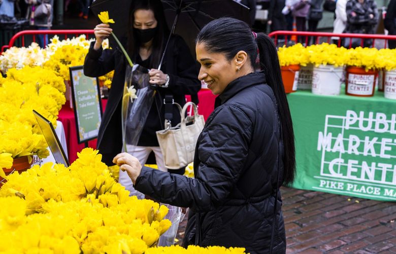 Claudia Carrillo of Tacoma, right, smiles as she picks daffodils at Pike Place Market’s 26th annual Daffodil Day celebration on the first day of spring on Monday, March 20, 2023.