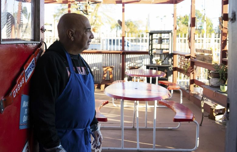 — EMBARGO: NO ELECTRONIC DISTRIBUTION, WEB POSTING OR STREET SALES BEFORE 3 A.M. ET ON SUNDAY, MARCH 19, 2023. NO EXCEPTIONS FOR ANY REASONS — Joe Faillace looks out onto the patio at The Olde Station Subway Shop, a sandwich shop that he and his wife have run in Phoenix, Ariz. for more than 30 years, on Feb. 10, 2023. In the past few years, a homeless encampment has been established around their small business, making their retirement plan of selling the business seem precarious. (Todd Heisler/The New York Times) XNYT119 XNYT119