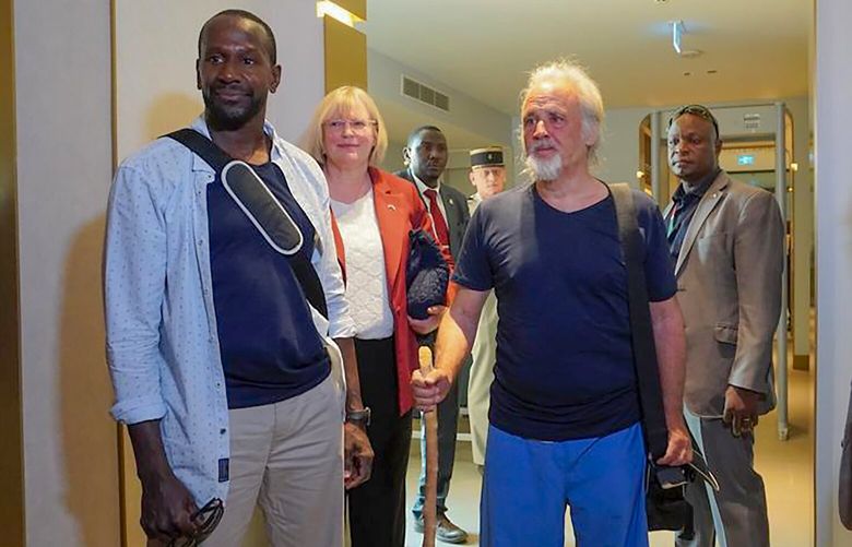 French journalist Olivier Dubois, left, and American aid worker Jeffery Woodke, center, arrive at the VIP lounge at the airport in Niamey, Niger, Monday March 20, 2023. Woodke was held by Islamic extremists in West Africa for more than six years and Dubois was abducted almost two years ago. The two men were the highest-profile foreigners known to be held in the region, and their release was the largest since a French woman and two Italian men were freed together in Mali back in Oct. 2020. (AP Photo/Judith Besnard) NIA101 NIA101
