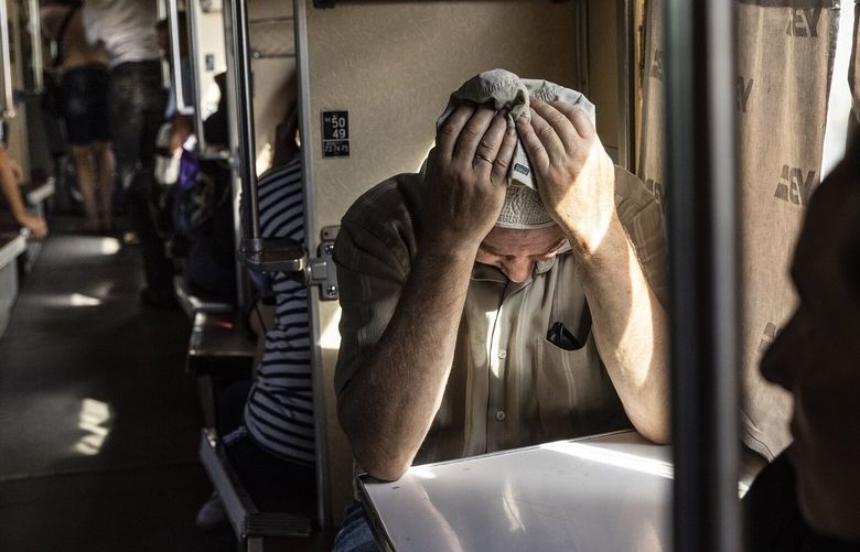 FILE — A man holds his head in his hands as he takes his seat on a train evacuating residents from Pokrovsk, Ukraine, July 31, 2022. Although Ukrainians excel at putting up a brave front, a tremendous amount of suffering is being kept bottled up and sometimes bursts out. (David Guttenfelder/The New York Times) XNYT52 XNYT52