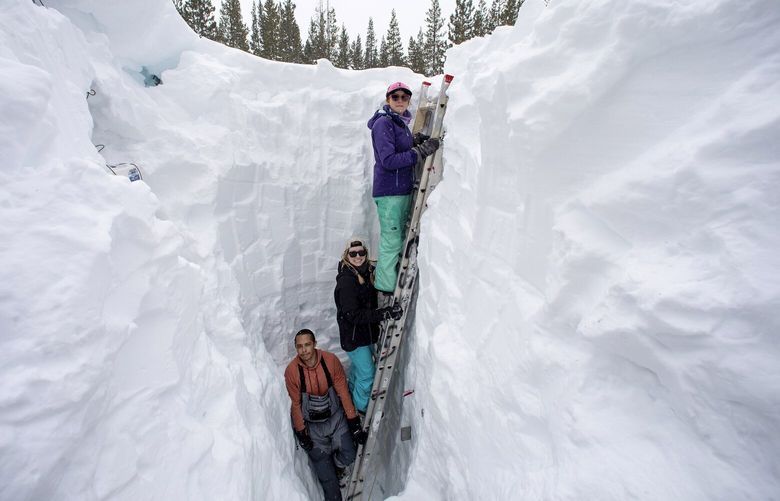 Working inside a nearly 18-foot-deep snow pit at the UC Berkeley Central Sierra Snow Lab, from left, Shaun Joseph, Claudia Norman, Helena Middleton take measurements of snow temperatures ahead of a weather storm on March 9, 2023, in Soda Springs, Calif. The more than 55 feet of snow that a dozen storms have dumped on the mountains along the Nevada-California line this season has etched its way into the history books as the second snowiest on record at the Central Sierra Snow Lab. (Karl Mondon/Bay Area News Group via AP) CAJOS201 CAJOS201