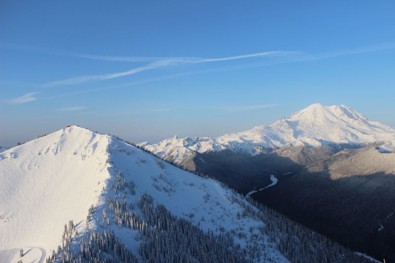 Silver Queen Mountain is crisscrossed with skier tracks in the morning light at Crystal Mountain Resort, while Mount Rainier looms large in the background.  (Gregory Scruggs / The Seattle Times)