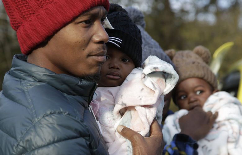 Haitian migrant Gerson Solay, 28, carries his daughter, Bianca, as he and his family cross into Canada at the non-official Roxham Road border crossing north of Champlain, N.Y., on Friday, March 24, 2023. A new US-Canadian migration agreement closes a loophole that has allowed migrants who enter Canada away from official border posts to stay in the country while awaiting an asylum decision. (AP Photo/Hasan Jamali) NYHJ102 NYHJ102