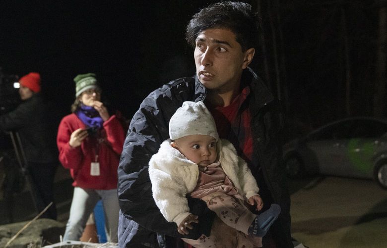Asylum seeker Mahamed Yusef Niazi, from Afghanistan, carries his seven-month-old daughter Sahaba, across the border at Roxham Road from New York into Canada on Friday, March 24, 2023 in Champlain, N.Y. The irregular border crossing will be closed permanently tonight at midnight. (Ryan Remiorz/The Canadian Press via AP) RYR134 RYR134