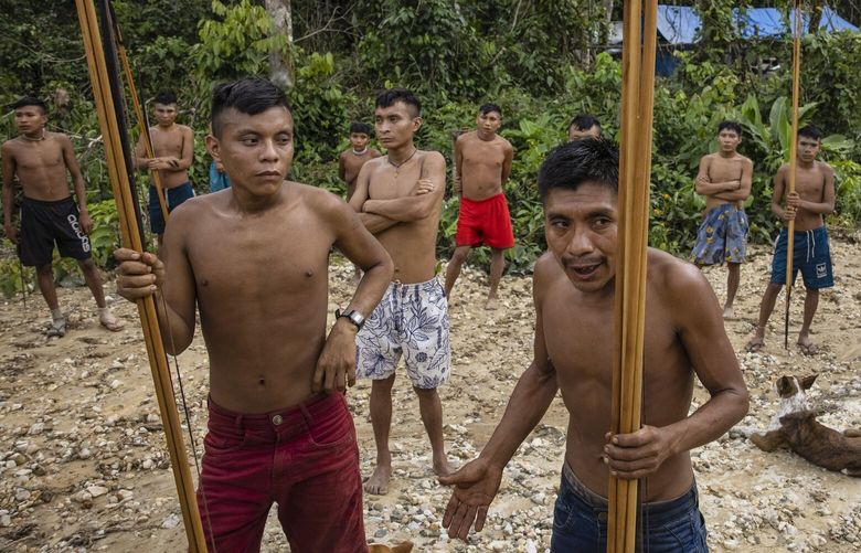 About two dozen Yanomami people, who emerged from the rainforest when members of Brazil’s environmental special forces team arrived to destroy illegal mining equipment in the Yanomami Indigenous territory of Brazil, on Feb. 24, 2023. An explosion of illegal mining in this vast swath of the Amazon has created a humanitarian crisis for the Yanomami people, cutting their food supplies, spreading malaria and, in some cases, threatening the Yanomamis with violence, according to government scientists and officials. (Victor Moriyama/The New York Times) XNYT120 XNYT120