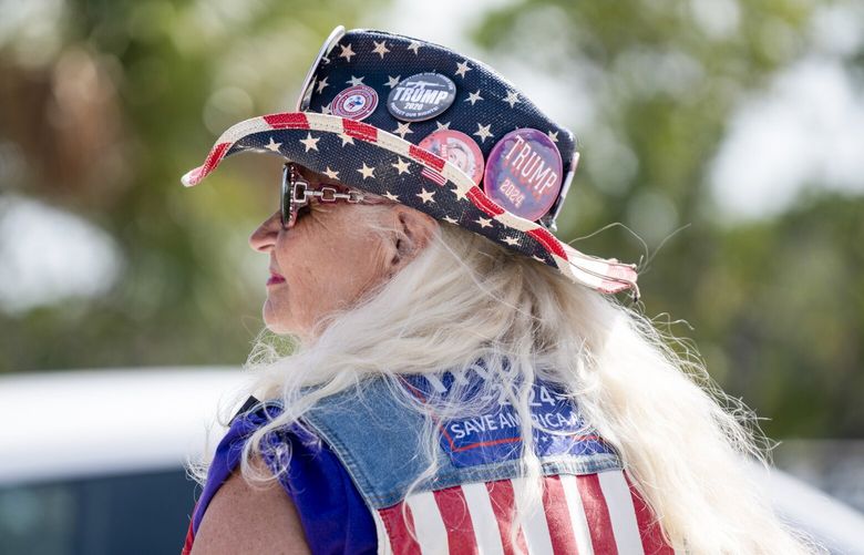 Kathy Clark wears a hat with pins in support of former President Donald Trump, who was indicted by a Manhattan grand jury on Thursday, on a bridge near his Mar-a-Lago Club in Palm Beach, Fla., March 31, 2023. A Manhattan grand jury voted to indict Trump on Thursday afternoon, and he is likely to be arraigned on Tuesday, when the charges against him will be formally unveiled. (Josh Ritchie/The New York Times) XNYT207 XNYT207