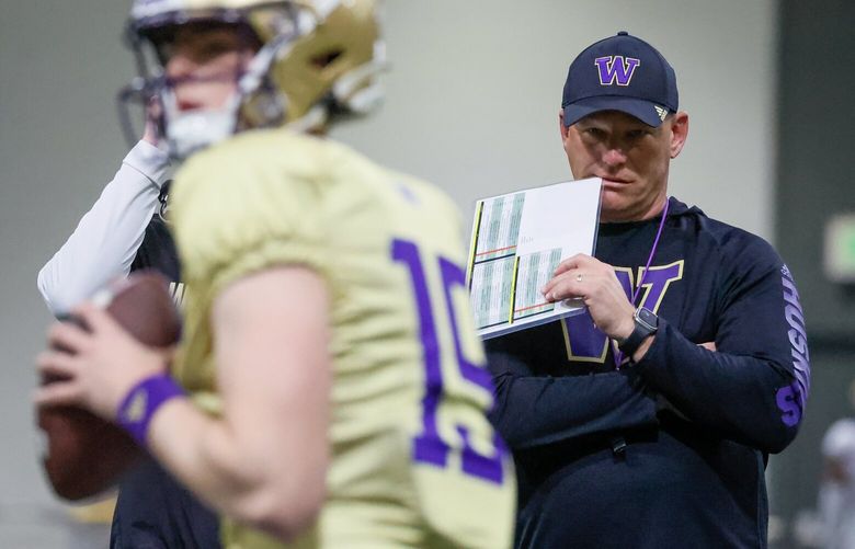 Quarterback Alex Johnson runs through a drill with head coach Kalen DeBoer looking on Friday morning in the Dempsey Indoor Center at the University of Washington in Seattle, Washington on March 31, 2023.