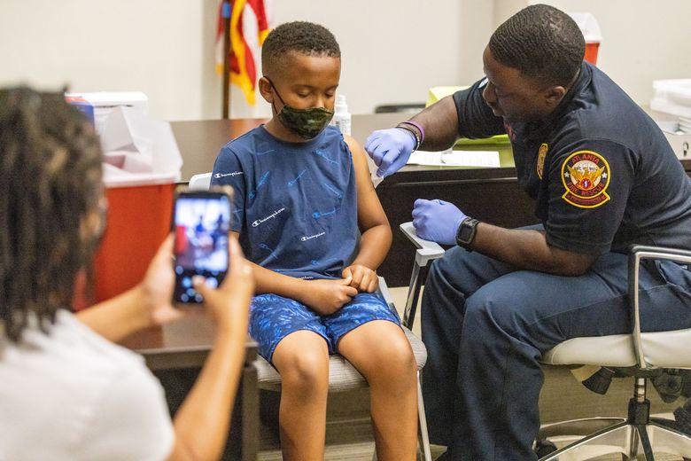 Xavier James, 11, gets ready to receive a COVID-19 shot as his mother takes his photograph during a vaccine event in Atlanta in summer 2022. In most of the country, Black children were vaccinated at lower rates than white children.  (Steve Schaefer/The Atlanta Journal-Constitution/TNS)