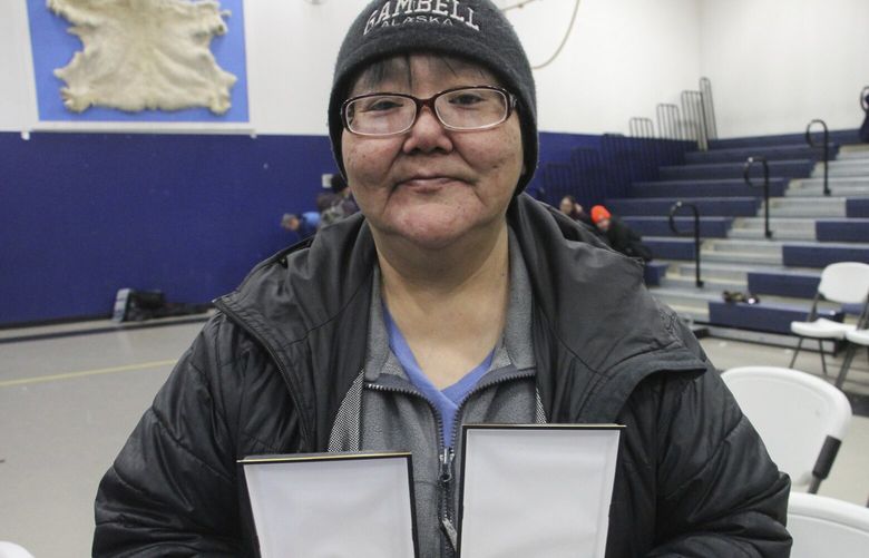 This March 28, 2023, photo shows JoAnn Kulukhon posing with two Alaska Heroism Medals presented posthumously to her uncles, Pvts. Luke and Leroy Kulukhon, during a ceremony in Gambell, Alaska. Sixteen Alaska National Guard members were honored for helping rescue the 11 crewmembers of a Navy plane that was shot down in 1955 by Soviet jet fighters and crash-landed about 8 miles from Gambell, on St. Lawrence Island, and 15 medals were presented posthumously. (AP Photo/Mark Thiessen) RPMT610 RPMT610
