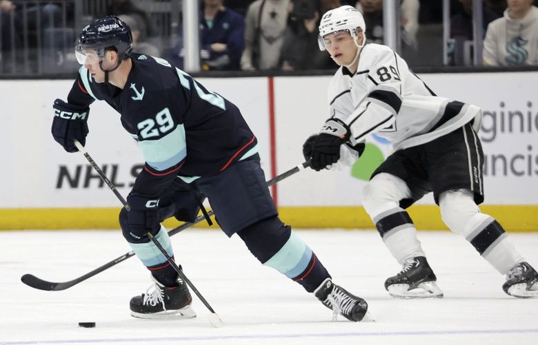 Seattle Kraken defenseman Vince Dunn (29) skates with the puck while under pressure from Los Angeles Kings center Rasmus Kupari (89) during the first period of an NHL hockey game, Saturday, April 1, 2023, in Seattle. (AP Photo/John Froschauer) WAJF105 WAJF105