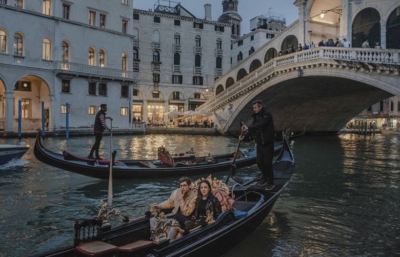 Gondolas pass under the Rialto Bridge in Venice, Italy on May 4, 2022. The sea walls have allowed life to go on as usual, but their incessant deployment, experts warn, could render Venice’s lagoon a fetid swamp choked by noxious algae, turning the city’s charming canals into stinking open sewers. (Laetitia Vancon/The New York Times) XNYT15 XNYT15