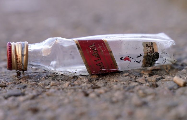 An empty miniature bottle that once contained liquor rests on a street near a sidewalk, Monday, April 3, 2023, in Boston.  A Boston city councilor has proposed barring city liquor stores from selling the single-serve bottles that hold 100 milliliters or less of booze both as a way to address alcohol abuse and excessive litter.  (AP Photo/Steven Senne) MASR203 MASR203