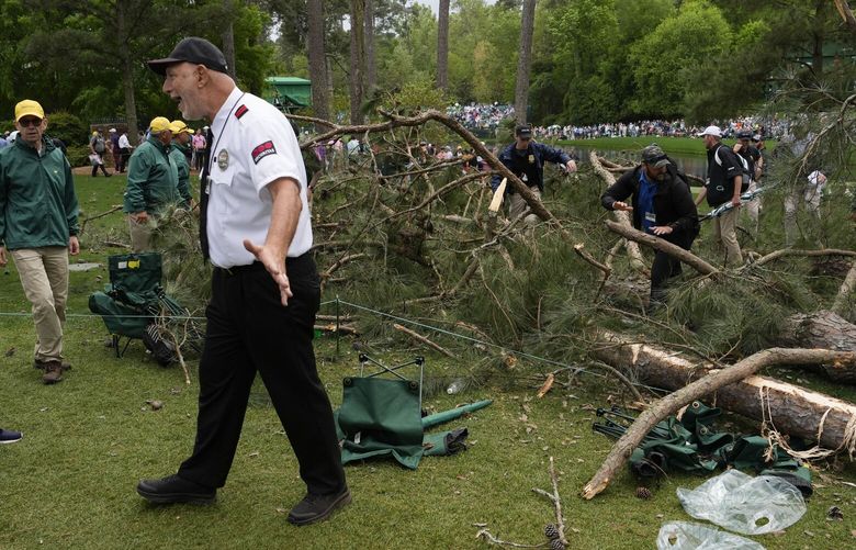 A security guard moves patrons away from trees that blew over on the 17th hole during the second round of the Masters golf tournament at Augusta National Golf Club on Friday, April 7, 2023, in Augusta, Ga. (AP Photo/Mark Baker) AUG330 AUG330