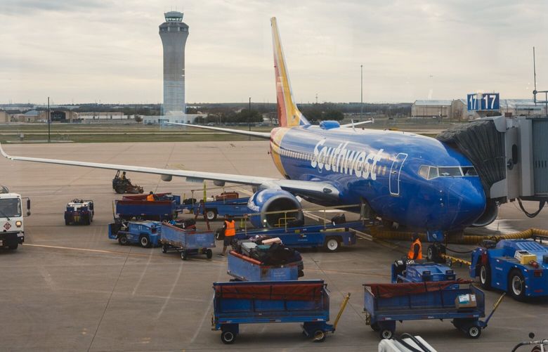 A Southwest aircraft at a gate in front of the air traffic control tower in Austin–Bergstrom International Airport.