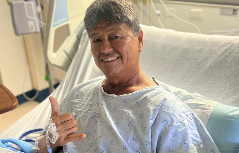 Mike Morita poses for a photo from his hospital bed, Wednesday, April 10, 2023, in Honolulu. Morita credits a faith in God for surviving an Easter Sunday shark attack and for remaining at peace despite losing his right foot. (Kamu Morita via AP) LA402 LA402