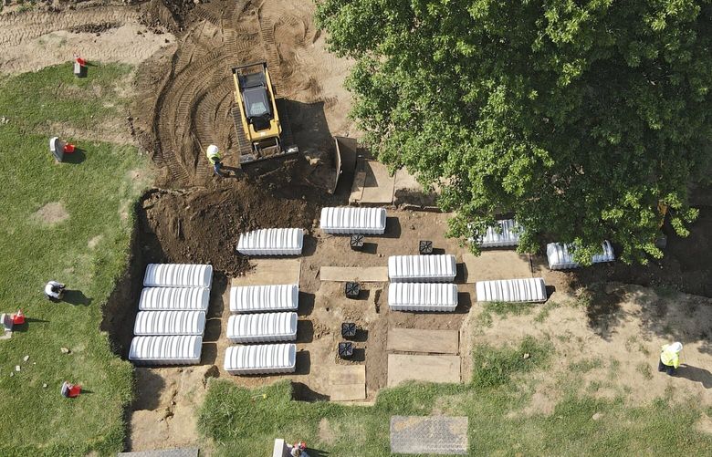 FILE – In this aerial photo, a mass grave is re-filled with dirt after a small ceremony at Oaklawn Cemetery, July 30, 2021, in Tulsa, Okla. The mass grave was discovered while searching for victims of the Tulsa Race Massacre. A forensic anthropologist believes investigators are a step closer to identifying victims of the 1921 Tulsa Race Massacre with the discovery of 19 surnames possibly connected to remains excavated from the Tulsa cemetery. (Mike Simons/Tulsa World via AP, File)/Tulsa World via AP) OKTUL301 OKTUL301