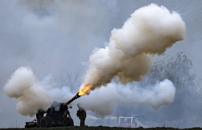 Servicemen of the United States 101 Airborne Division fire an artillery piece, not using live ammunition, as an Apache gunship hovers above during an exercise at the Mihail Kogalniceanu Air Base, near the Black Sea port of Constanta, Romania, Friday, March 31, 2023. The United States 101 Airborne Division currently deployed in Romania to bolster NATO’s eastern flank held a ceremony and air assault demonstration to mark the rotations of its Strike brigade with the Bastogne brigade. (AP Photo/Vadim Ghirda) XVG109 XVG109