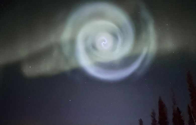 In this photo provided by Christopher Hayden, a light baby blue spiral resembling a galaxy appears amid the aurora for a few minutes in the Alaska skies near Fairbanks, Saturday, April 15, 2023.  The spiral was formed when excess fuel that had been released from a SpaceX rocket that launched from California about three hours earlier turned to ice, and then the water vapor reflected the sunlight in the upper atmosphere. (Christopher Hayden via AP) FX104 FX104