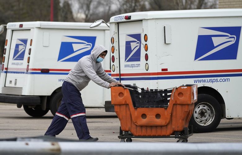 FILE – A USPS employee works outside post office in Wheeling, Ill., Dec. 3, 2021. The U.S. Postal Service delivered more than 54 million ballots for the midterm election, with nearly 99% of ballots delivered to election officials within three days, officials said Monday, Jan. 9, 2023. (AP Photo/Nam Y. Huh, File)