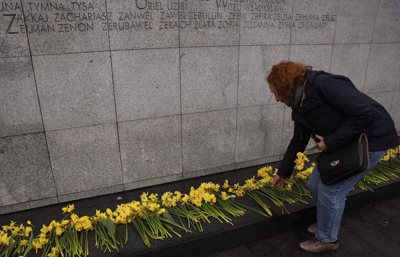 A woman places a yellow tulip at ‘The Umschlagplatz’ monument during personal unofficial observances marking the 80th anniversary of the Warsaw Ghetto Uprising in Warsaw, Poland, Wednesday, April 19, 2023. (AP Photo/Michal Dyjuk) DYJ123 DYJ123