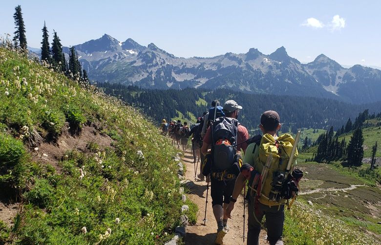 Tatoosh Ridge towers in the distance as hikers descend the Skyline Trail.