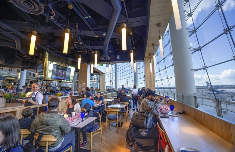Diners can watch airplanes on the tarmac and in the air as they eat and drink at Salty’s at the SEA restaurant. (Ellen M. Banner / The Seattle Times)