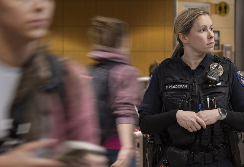 Emily Holdeman, a Port of Seattle police officer, watches as passengers walk by in the baggage claim area at Seattle-Tacoma International Airport. She often answers questions and helps people through the airport. (Ellen M. Banner / The Seattle Times)