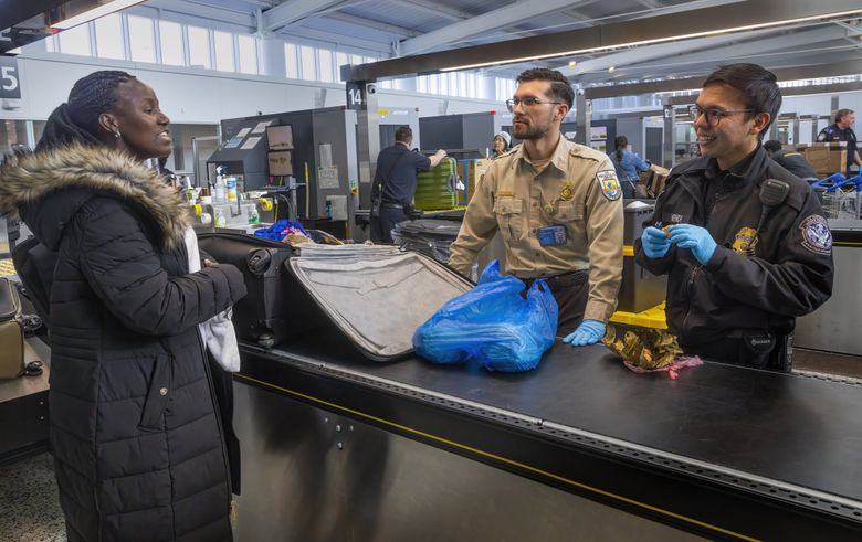 Passenger Alice Sesay, left, speaks to Anthony Gilmore, U.S. Fish &#038; Wildlife inspector, center, and Robert Mendi, agricultural specialist, as she goes through customs after an international flight to Sea-Tac Airport. (Ellen M. Banner / The Seattle Times)