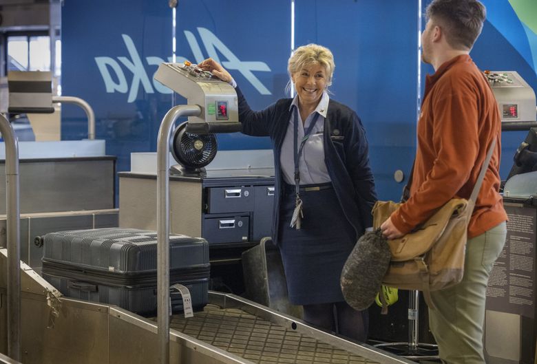 Susanna Poier, a customer service agent for 16 years at Alaska Airlines, checks a passenger’s luggage at Sea-Tac Airport. (Ellen M. Banner / The Seattle Times)