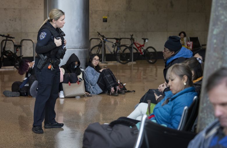 Emily Holdeman, a Port of Seattle police officer, asks a man in the baggage claim area if he is loitering at the airport. He was and she asked him to go outside. (Ellen M. Banner / The Seattle Times)