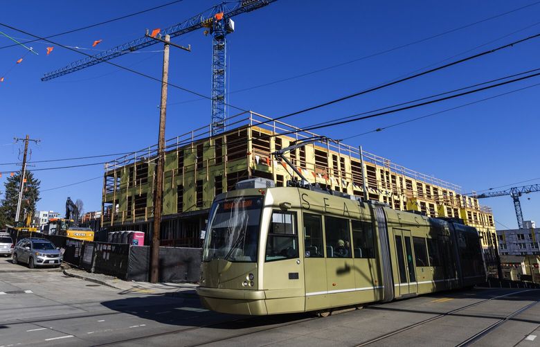 Light-rail zips past the Wayfarer Apartments under construction as building continues at Yesler Terrace, Sunday, Jan. 29, 2023 in Seattle. More market-rate housing has developed around Yesler Terrace, which is Washington State’s first public housing development, opening in the 1940s; and at the time it became the first racially integrated public housing development in the United States.