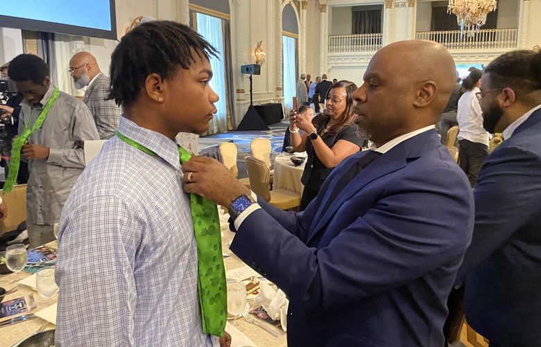 Amari Jackson gets assistance with his new necktie from Seattle Public Schools Superintendent Brent Jones tie at the Tie One On luncheon at the Olympic Fairmont Hotel. (Courtesy of Carlton Whitehead)
