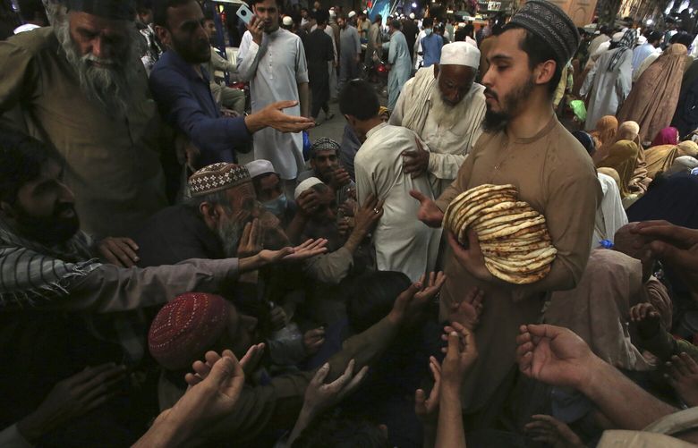 A worker distributes free traditional roti or bread among needy people at a restaurant, in Peshawar, Pakistan, Sunday, April 16, 2023. People are suffering from recent price hike in food, gas, fuel, and power in Pakistan. (AP Photo/Muhammad Sajjad) NYPM807 NYPM807