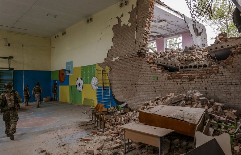 FILE – Ukrainain soldiers walk through a school gymnasium damaged during fightings with Russia, in the Mykolaiv region of southern Ukraine, Aug. 11, 2022. A copy of an unreleased independent review obtained by The New York Times is critical of a report by the rights group Amnesty International that accused Ukrainian forces of a pattern of illegally endangering civilians while fighting Russia. (Daniel Berehulak/The New York Times) XNYT300 XNYT300