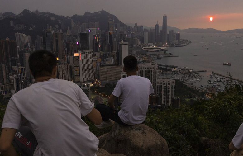 FILE – Mainland Chinese tourists look at sunset from a hill in Hong Kong, April 26, 2023. Living in Hong Kong today means juggling contradictory feelings. In 20 interviews, many said that when they focus on business indicators and everyday life, they see a recovery gathering pace after years of travel restrictions. But when it comes to anything political, the openness and freedoms that were once hallmarks of the Chinese-ruled former British colony seem permanently gone. (AP Photo/Louise Delmotte, File) XLD101 XLD101