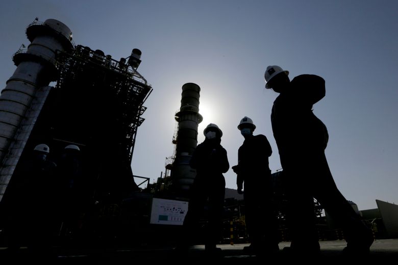 FILE – Saudi Aramco engineers walk in front of a gas turbine generator at Khurais oil field during a tour for journalists, 150 kilometers east-northeast of Riyadh, Saudi Arabia on June 28, 2021. Saudi Arabia said Sunday, April 2, 2023, it will cut oil production by 500,000 barrels per day from May until the end of 2023. (AP Photo/Amr Nabil, File)