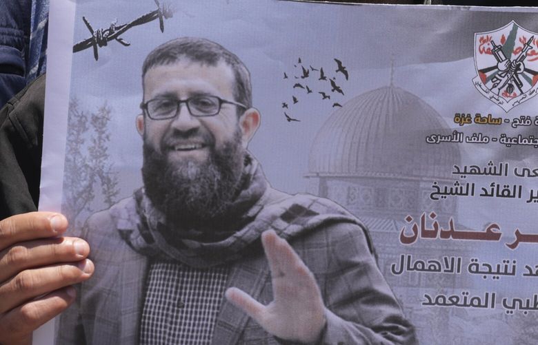 A Palestinian holds a picture of Khader Adnan, a leader in the militant Islamic Jihad group, who died in Israeli prison after a nearly three-month hunger strike, during a sit-in in front of the International Committee of the Red Cross office, in Gaza City, Tuesday, May 2, 2023. Arabic on a picture reads ” Fatah mourns the martyr, prisoner and leader Khader Adnan, was killed due to deliberate medical negligence.” Adnan had begun staging protracted hunger strikes more than a decade ago, introducing a new form of protests against Israel’s mass detentions of Palestinians without charges or trials. (AP Photo/Adel Hana) XAH104 XAH104