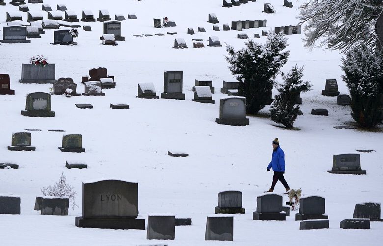 FILE – A man walks through the snow covered Mount Lebanon Cemetery in Mount Lebanon, Pa., on Monday, Jan. 23, 2023. U.S. deaths fell in 2022, as COVID-19 fatalities dropped by half from 2021 and the coronavirus dropped from being the nation’s third leading cause of death to the fourth. The Centers for Disease Control and Prevention reported the 2022 numbers on Thursday, May 4, 2023, cautioning that they are preliminary and may change a little after further analysis. (AP Photo/Gene J. Puskar, File) NY608 NY608