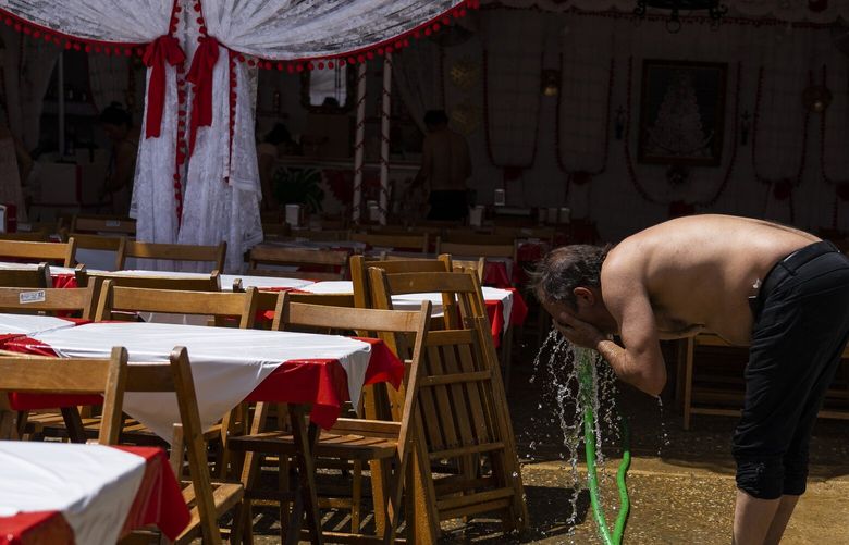 FILE – A man cools himself with water outside a ‘caseta’ (tent where food and drinks are served) in the annual traditional April Fair in Seville, Spain, April 27, 2023. Record-breaking April temperatures in Spain, Portugal and northern Africa were made 100 times more likely by human-caused climate change, a new flash study found. (AP Photo/Santi Donaire, File) CLI203 CLI203