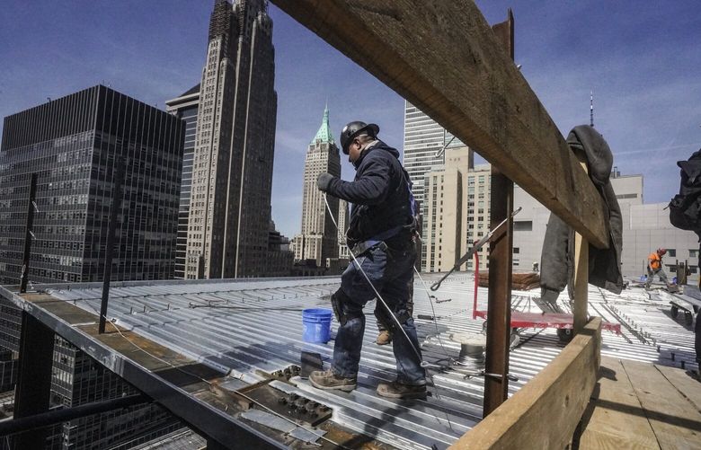 Construction workers install roofing on a high rise in Manhattan’s financial district on Tuesday, April 11, 2023, in New York. On Friday, the U.S. government issued the April jobs report. (AP Photo/Bebeto Matthews, File) 
